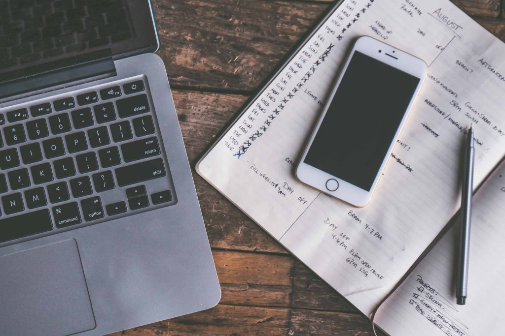 Computer and cell phone next to calendar with appoitnments